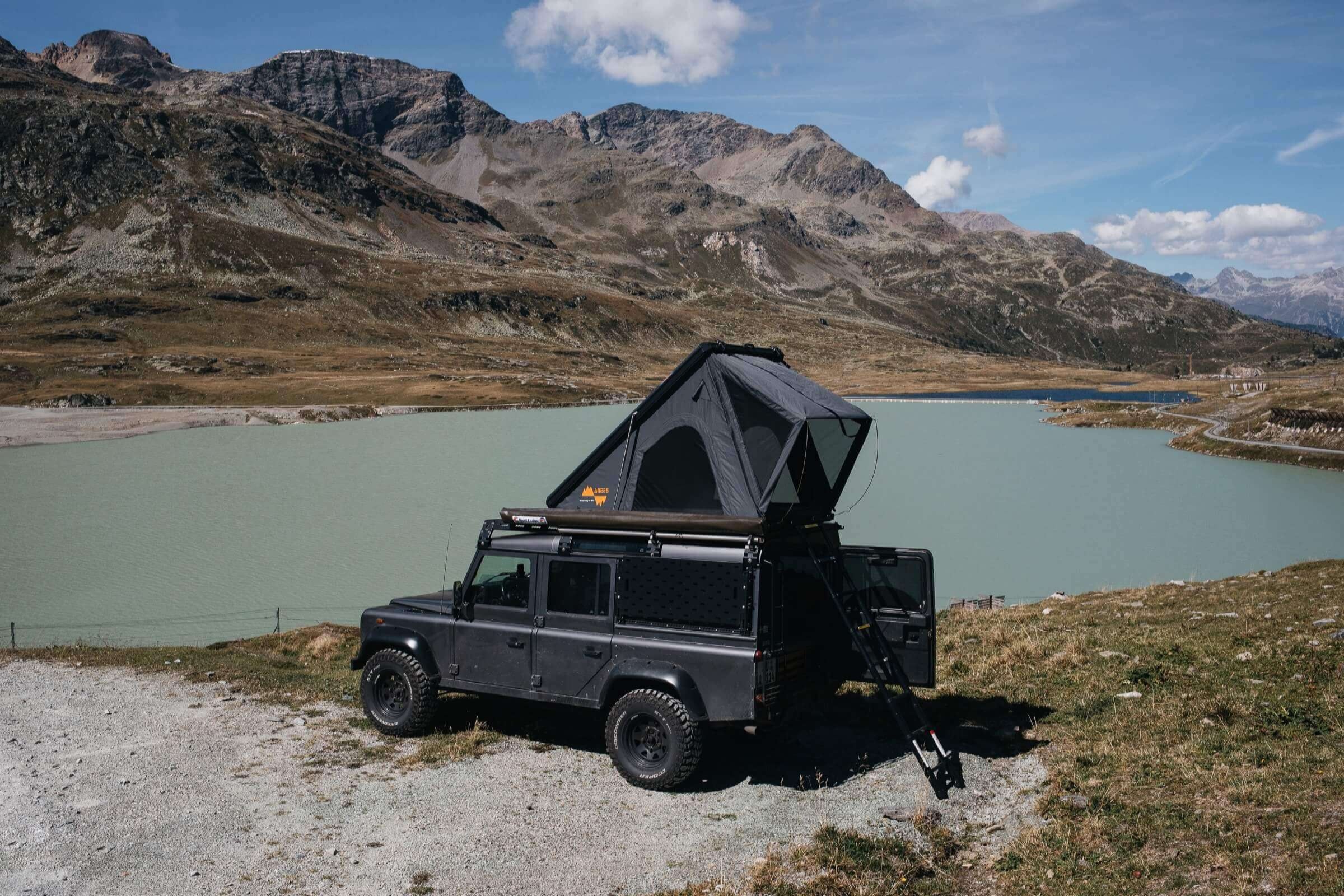 Triangle Dachzelt auf Geländewagen am Bergsee mit Alpenpanorama